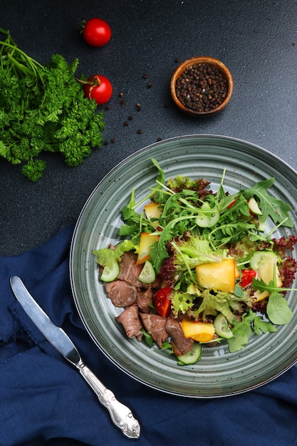 Insalata di lingua di manzo con parmigiano e verdure su sfondo di cemento scuro o tavolo con vista dall'alto di ingredienti