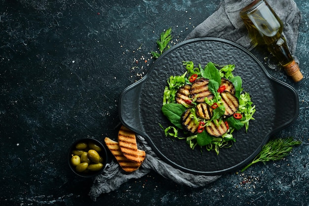 Insalata di melanzane, spinaci e cavoli su un piatto nero Cibo vegano Vista dall'alto Stile rustico