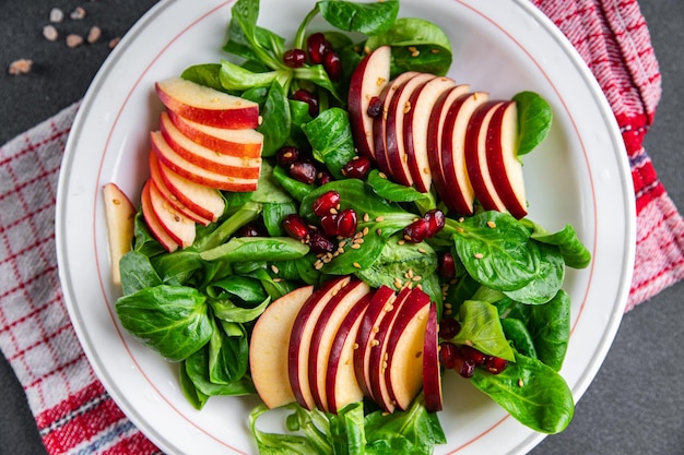 insalata di mele fresca, lattuga mista verde, spuntino sano pasto pasto grano melograno sul tavolo