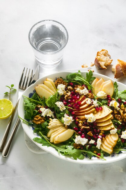 Insalata di melograno e verde pera con salsa allo zenzero su marmo bianco. colazione o pranzo salutari