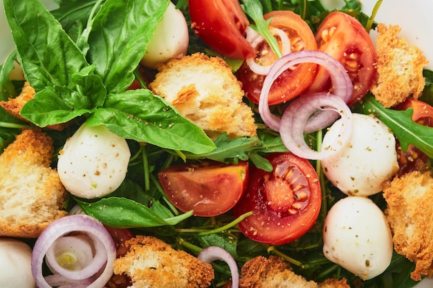 Insalata di pane Panzanella Cibo tradizionale italiano con pomodori, mozzarella, palline, basilico, cipolla e pane su sfondo grigio chiaro Cucina tradizionale italiana Vista dall'alto Spazio di copia