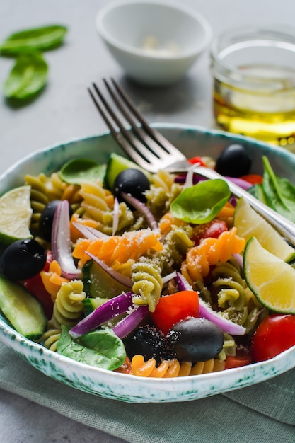 Insalata di pasta con fusilli colorati e verdure in un piatto di ceramica