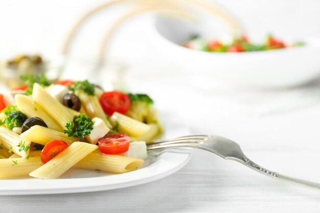 Insalata di pasta con pomodori e oliva sulla tavola di legno