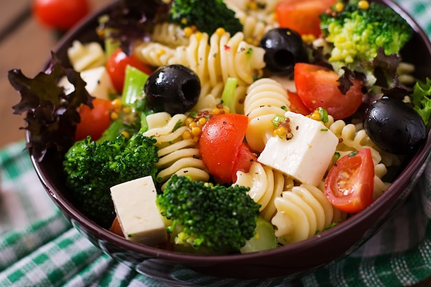 Insalata di pasta con pomodoro, broccoli, olive nere e formaggio feta.