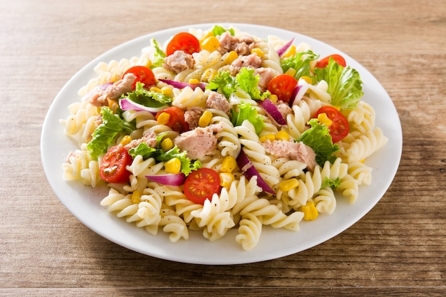 Insalata di pasta con verdure e tonno sul tavolo di legno.