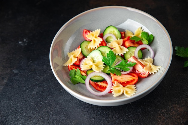 Insalata di pasta farfalle pomodoro cetriolo cipolla pasto sano spuntino dietetico sul tavolo