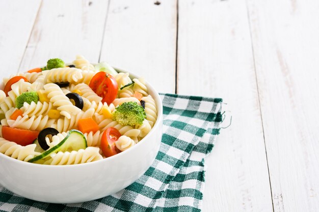 Insalata di pasta in una ciotola sullo spazio di legno bianco della copia della tavola