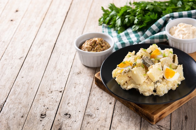 Insalata di patate con cetriolini, uova e senape su tavola di legno