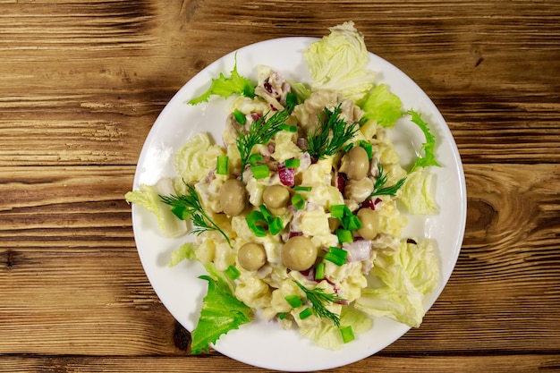 Insalata di patate con funghi marinati uova cipolla rossa e maionese su tavola di legno