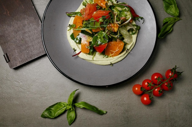 insalata di peperoni, pomodori, erbe aromatiche e lattuga su un piatto grigio