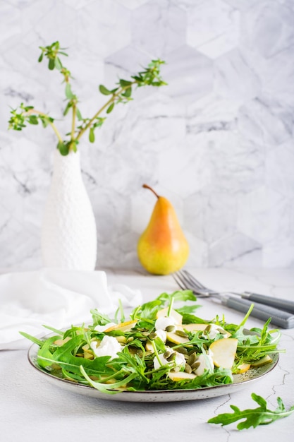 Insalata di pere con rucola e semi di zucca su un piatto Pranzo vitaminico fatto in casa Vista verticale