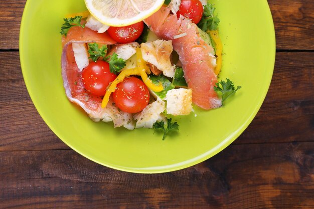 Insalata di pesce fresco con verdure sul piatto sul primo piano della tavola di legno