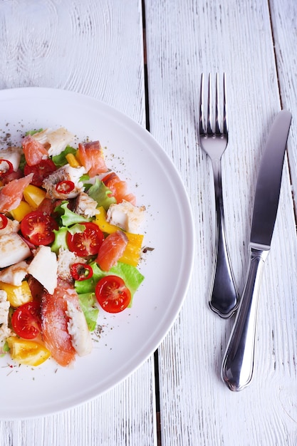 Insalata di pesce fresco con verdure sul piatto sul primo piano della tavola in legno