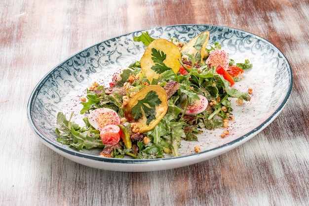 Insalata di petto d'anatra con patatine fritte e verdure fresche Su un piatto decorativo