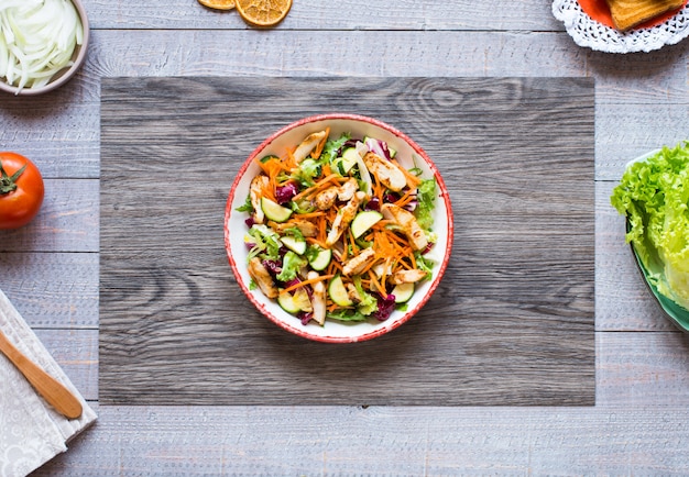 Insalata di petto di pollo con zucchine e pomodorini, su una superficie di legno