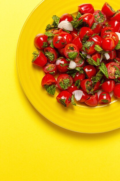 Insalata di pomodori ciliegia fatta in casa con cipolle fresche, menta, olio d'oliva e sale