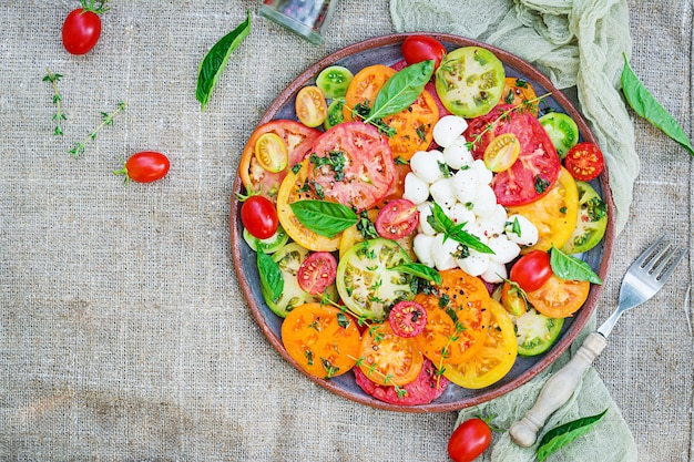 Insalata di pomodori colorati con mozzarella e basilico al formaggio. Insalata caprese. Cibo vegano. Vista dall'alto