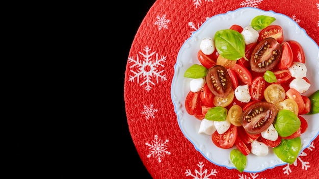 Insalata di pomodori con mozzarella e basilico per la cena di Natale. Piatto vegetariano.