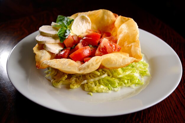 Insalata di pomodori mozzarella e caprese di basilico in tortilla fritta su piatto bianco