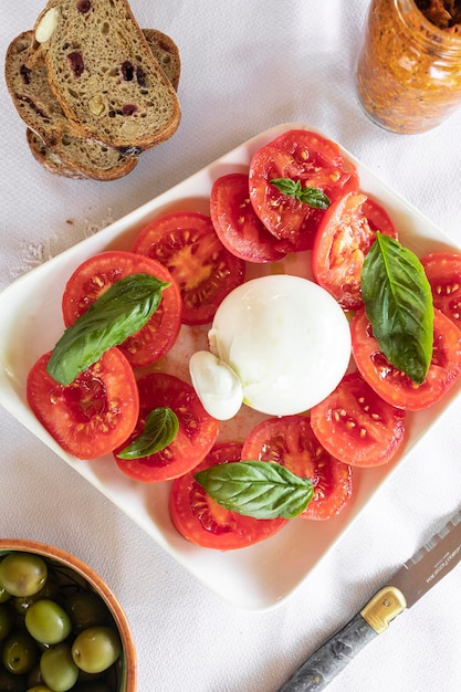 Insalata di pomodori rossi con burrata e foglie di basilico fresco Insalata alla mediterranea