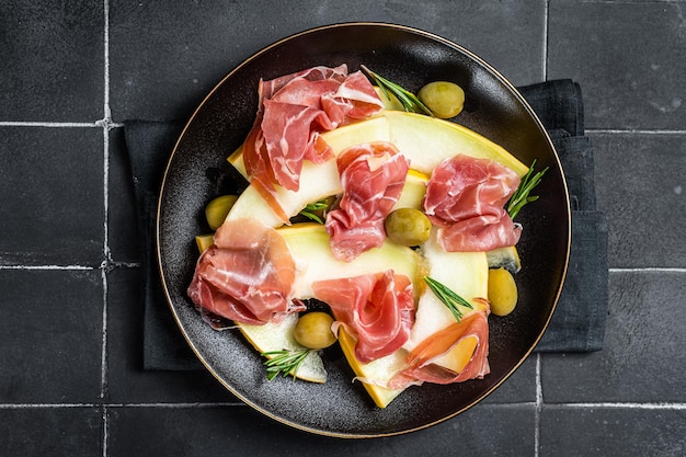 Insalata di prosciutto e melone in un piatto Sfondo nero Vista dall'alto