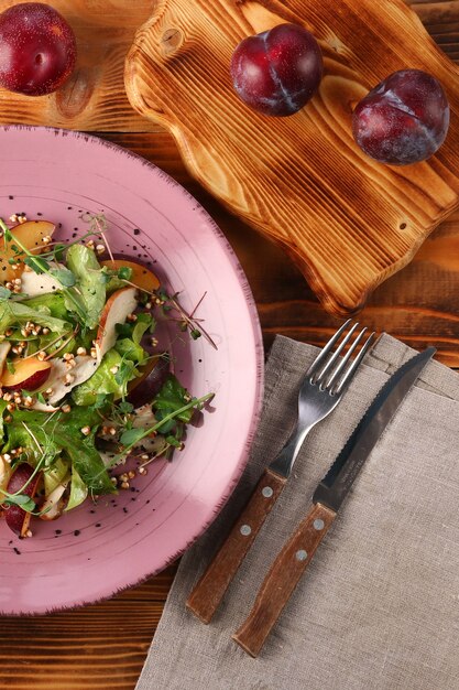 Insalata di prugne con erme microgreen e pinoli nel piatto sulla tavola di legno