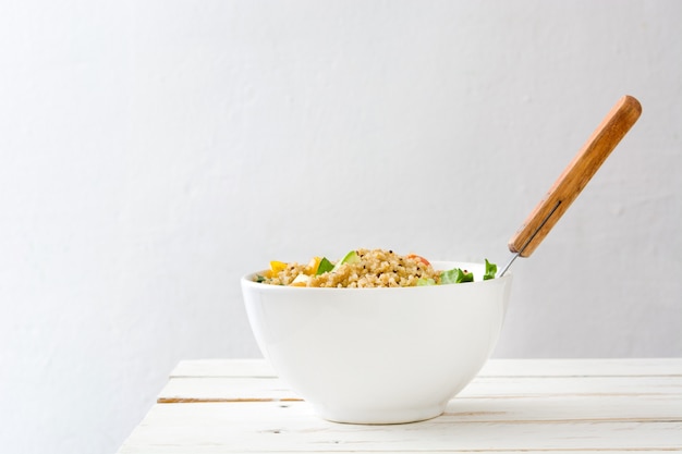 Insalata di quinoa in ciotola sul tavolo di legno bianco