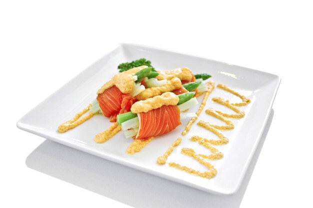 Insalata di rotoli di formaggio salmone fresco asparagi su piatto bianco isolato