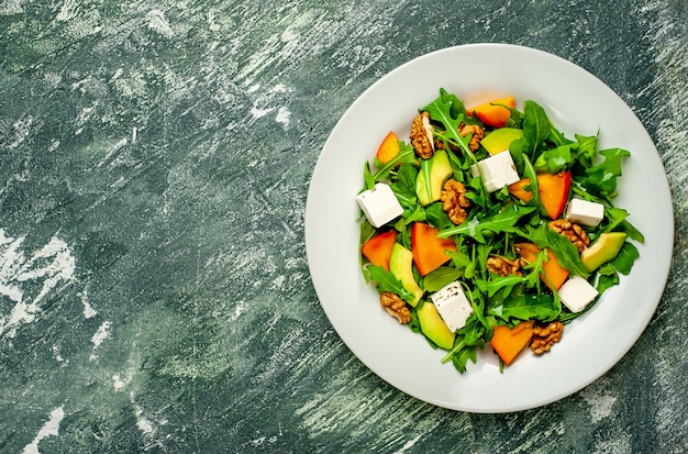 Insalata di rucola, formaggio, barbabietola, noce, sullo sfondo di ardesia, pietra o cemento.