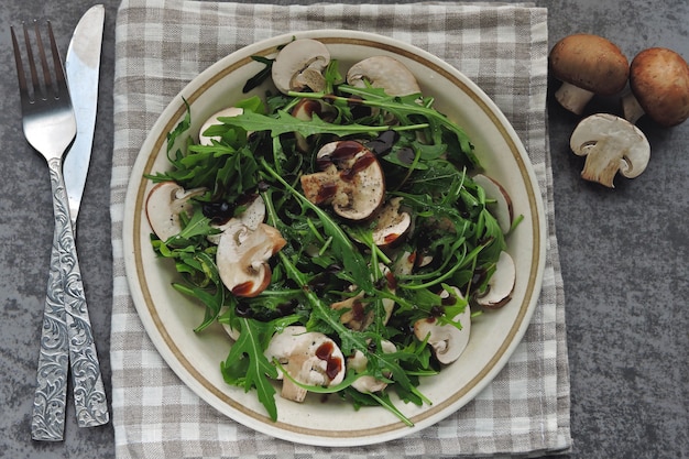 Insalata di rucola sana con funghi prataioli crudi con olio d'oliva e salsa di soia Insalata vegana con funghi crudi.