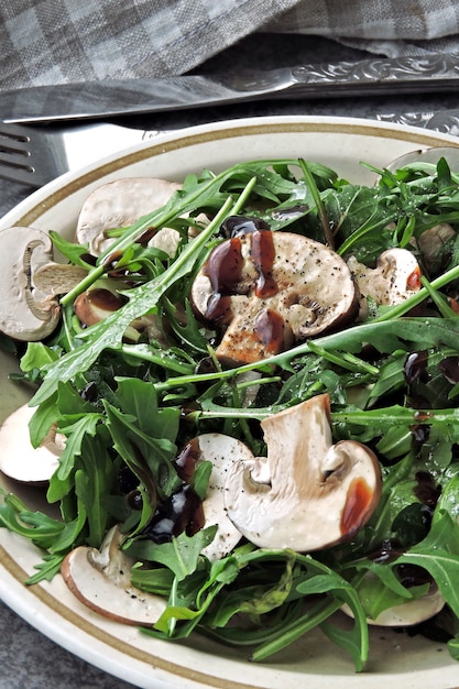 Insalata di rucola sana con funghi prataioli crudi con olio d'oliva e salsa di soia Insalata vegana con funghi crudi.