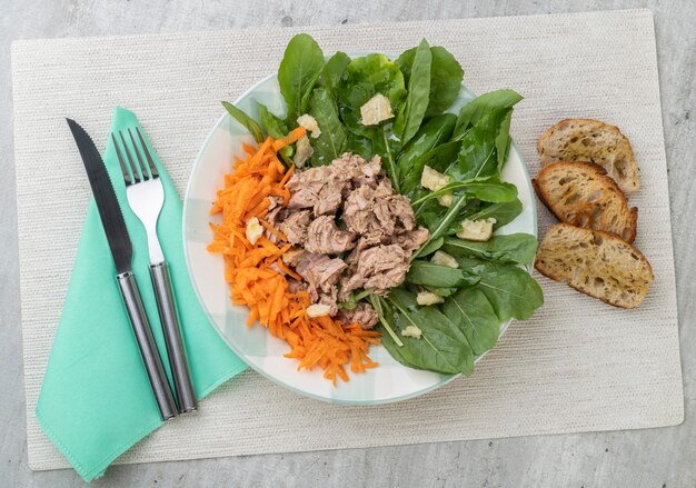 Insalata di rucula, tonno, parmigiano e carote con pane tostato.