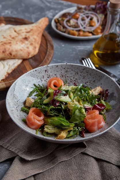 Insalata di salmone con spinaci pomodorini insalata di mais spinaci baby menta fresca e basilico Cibo fatto in casa Concetto per un pasto gustoso e sano Sfondo di pietra scura Vista dall'alto Primo piano