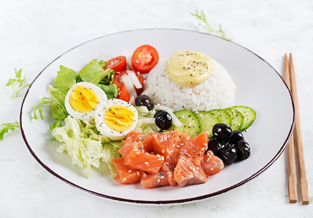 Insalata di salmone fresco biologico con riso uovo sodo pomodori cetrioli e olive nere Concetto di nutrizione per il pranzo di cibo veloce e sano