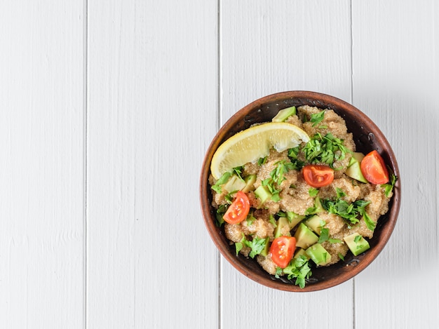 Insalata di semi di amaranto, avocado, pomodori, limone e prezzemolo con olio d'oliva su un tavolo. La vista dall'alto.