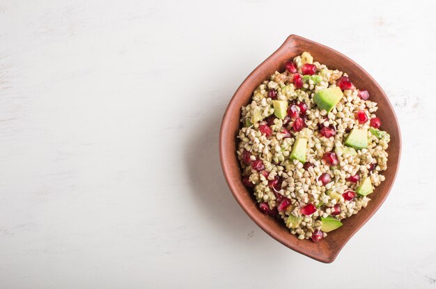 Insalata di semi di grano saraceno germogliato, avocado, noce e melograno in piatto di argilla