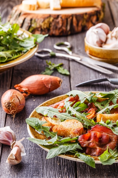 Insalata di tarassaco fresca con pancetta fritta e crostini all'aglio.