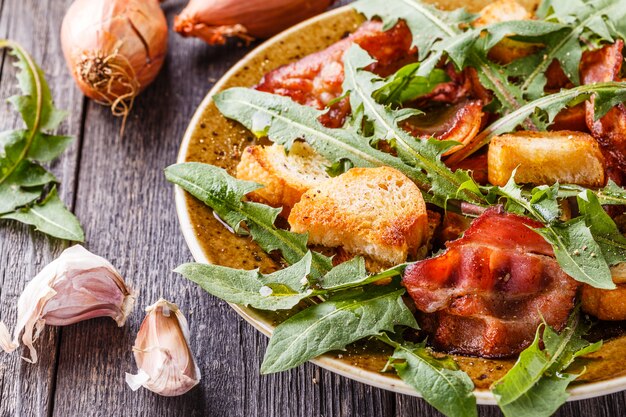 Insalata di tarassaco fresca con pancetta fritta e crostini all'aglio.