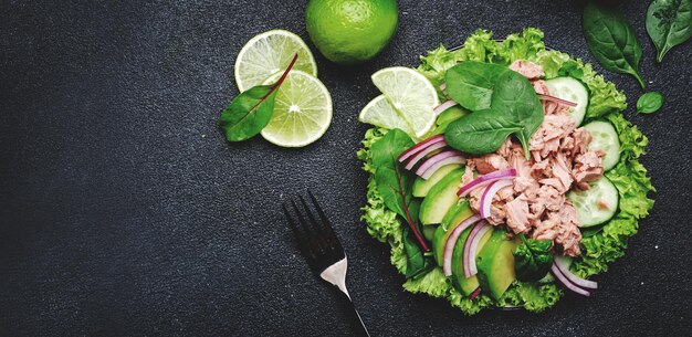 Insalata di tonno con cetriolo avocado cipolla rossa spinaci e lattuga Sfondo in pietra bianca vista dall'alto spazio per la copia