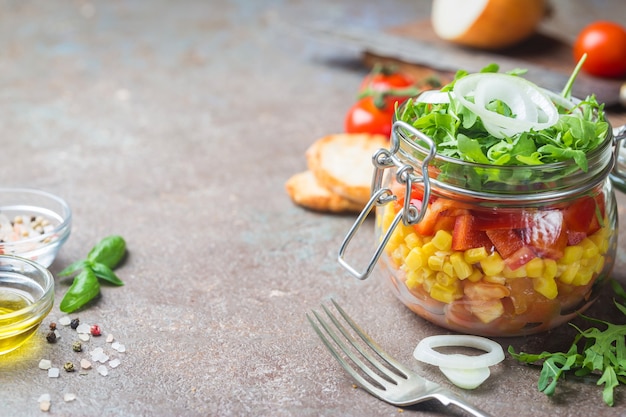 Insalata di verdure casalinga sana del barattolo di muratore con pomodori, mais, pepe, rucola e cipolla