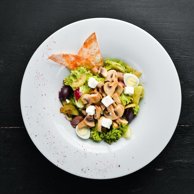 Insalata di verdure con funghi, olive e feta. Nel piatto. Vista dall'alto. Spazio libero per il tuo testo. Stile rustico.