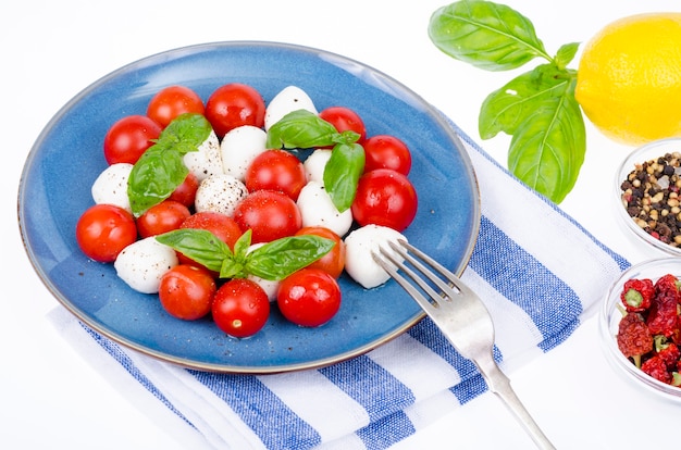 Insalata di verdure con palline di mozzarella sul piatto, sfondo bianco. Foto dello studio.