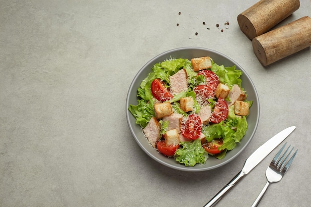 Insalata di verdure con pollo e formaggio su un tavolo grigio Insalata Caesar in un piatto grigio