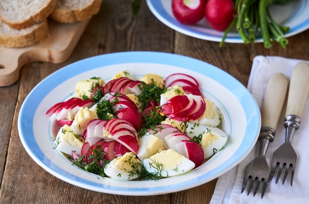 Insalata di verdure con ravanelli, aneto e uova su un tavolo di legno