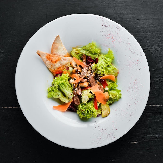 Insalata di verdure con vitello e funghi. Nel piatto. Vista dall'alto. Spazio libero per il tuo testo. Stile rustico.