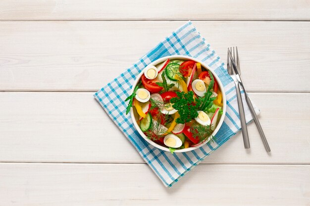 Insalata di verdure di iceberg di pomodoro cetriolo pepe e uova di quaglia piatto bianco orizzontale