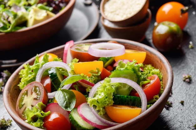 Insalata di verdure di lattuga pomodorini ravanello cetriolo cipolla e basilico su vassoio in pietra di ardesia