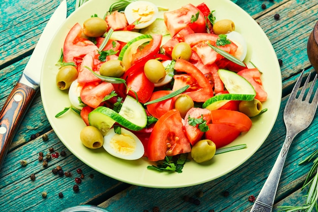 Insalata di verdure di pomodori, cetrioli, olive e uova su fondo di legno