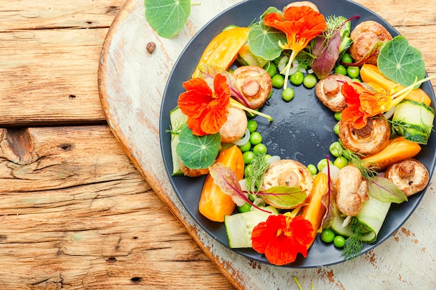 Insalata di verdure estive decorata con fiori di nasturzio. Cibo vegetariano sano