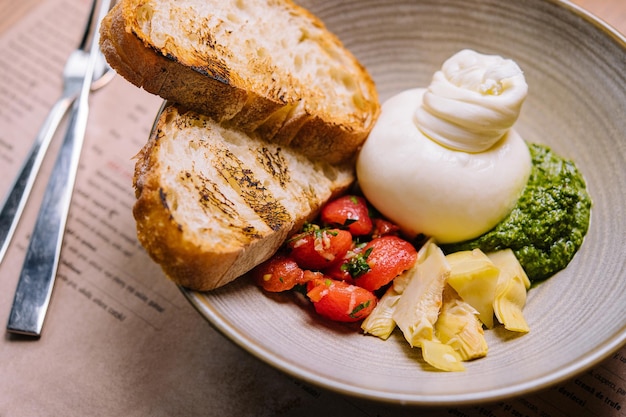 Insalata di verdure fresche con burrata bianca morbida e pesto verde da vicino